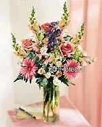Florero de vidrio con flores mixtas y rosas