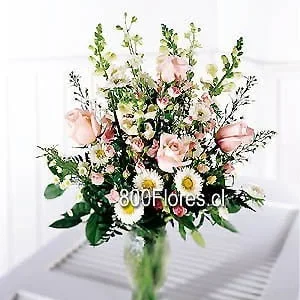 Florero de vidrio con flores mixtas y rosas